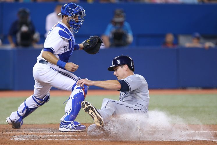 The Rays’ Kelly Johnson slides home with the go-ahead run in the eighth inning in front of Jays catcher J.P. Arencibia. (Photo courtesy of Getty Images)