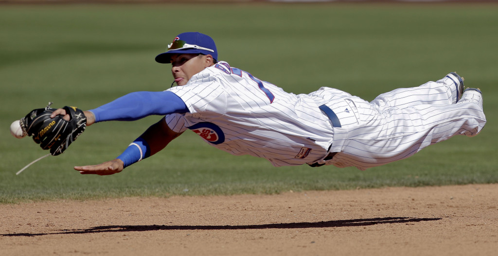 Chicago Cubs shortstop Javier Baez cannot get a glove on a base hit by Colorado Rockies' Eric Young Jr. (Photo Credit: AP Photo/Chris Carlson)